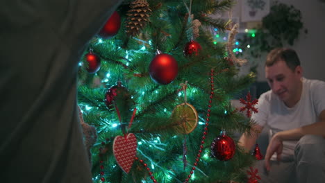 Eine-Familie-Mit-Zwei-Kindern-Schmückt-Am-Heiligabend-Einen-Weihnachtsbaum.-Vater-Und-Mutter-Mit-Kindern-Bereiten-Sich-Auf-Die-Dekoration-Des-Hauses-Für-Neujahr-Und-Weihnachten-Vor.-Hochwertiges-4K-Filmmaterial